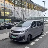 Srebrny bus czeka na pasażerów przed nowoczesnym terminalem lotniska. Może to być transport z Koszalina do Gdańska na lotnisko.