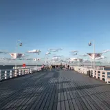 Spacer po molo w Sopocie, idealne miejsce na spacer po przyjeździe z Gdańska. Widać ludzi, ławki i latarnie.