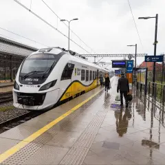 Pasażerowie wsiadają do pociągu, a obok stoi hulajnoga elektryczna.