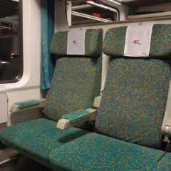 Wnętrze wagonu PKP Intercity. Widok na dwa rzędy siedzeń z charakterystycznym wzorem. Wybór miejsca ze schematu jest kluczowy dla komfortowej podróży.