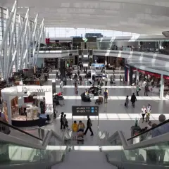 Tętniący życiem terminal lotniska w Budapeszcie. Ludzie poruszają się po nowoczesnej przestrzeni, szukając transportu z lotniska, sklepów i kawiarni.