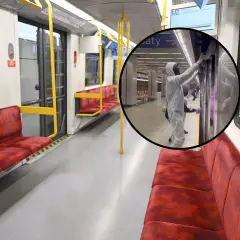 Wnętrze pustego wagonu metra M2, gdzie pracownicy w kombinezonach dezynfekują drzwi.