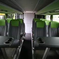 Wygodne, zielono-szare fotele w autobusie FlixBus, z rozkładanymi stolikami i uchwytami na kubki.