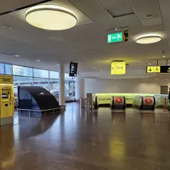 Żółte automaty biletowe Arlanda Express i schody ruchome prowadzące do pociągu.