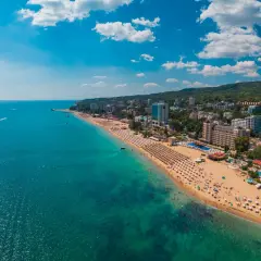 Słoneczna plaża w Złote Piaski, z turkusowym morzem i hotelami w tle. Idealne miejsce na wakacje, niedaleko lotniska.