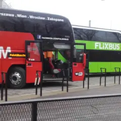 Dwa autokary Flixbus stoją obok siebie. Czerwony autokar ma otwarte drzwi, a zielony autokar z napisem FLIXBUS oferuje zniżki dla emerytów.