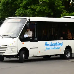 Białe autobusy w Żorach oferują bezpłatną komunikację miejską. Kierowca i pasażerowie w środku.