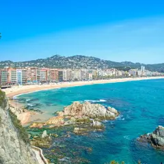 Widok na plażę w Lloret de Mar z klifów. W oddali widać zabudowania i wzgórza. Idealne miejsce na wakacje, niedaleko od lotniska.