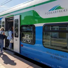 Pasażerowie wsiadają do pociągu Podkarpackiej Kolei Aglomeracyjnej. Na drzwiach widnieje symbol roweru.