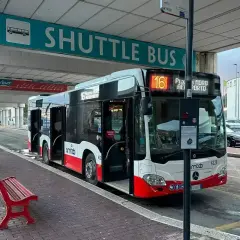 Autobus wahadłowy na lotnisku Bari czeka na pasażerów pod zielonym znakiem "SHUTTLE BUS".