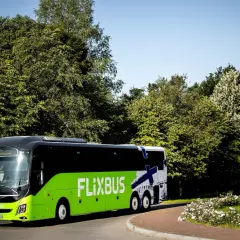Zielony Flixbus na tle zieleni i błękitnego nieba. Piękne miejsce na podróż.