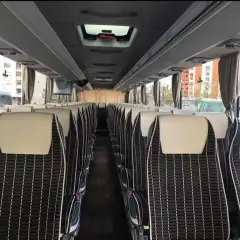 Wnętrze autobusu ze Słowenii, rzędy wygodnych siedzeń z czarno-białą tapicerką i jasnymi zagłówkami.