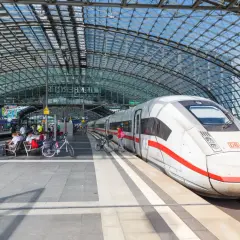 Biały pociąg ICE na peronie pod szklanym dachem. Berlin Dworzec Główny, ludzie czekają na pociąg z rowerami.
