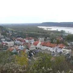 Widok na Kazimierz Dolny z rzeką Wisłą w tle. Planujesz podróż? Sprawdź, jak dojechać do Kazimierza Dolnego pociągiem.