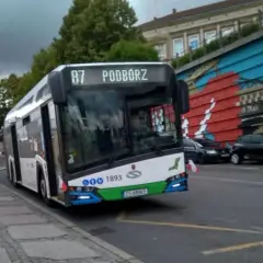 Autobus linii 87 w Szczecinie z napisem "Podwórze" na wyświetlaczu, zbliża się do przystanku.