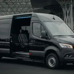 Czarny bus z Niemiec do Polski, z adresu pod adres. Komfortowe fotele i niebieskie oświetlenie wnętrza.