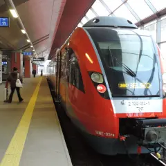 Czerwony pociąg na stacji, gotowy do odjazdu. Znak informuje o peronie 1, sektorze 3 i torze 11. Taryfa Małopolska obowiązuje na tej trasie.
