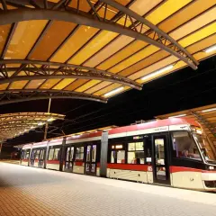 Nowoczesne gdynia tramwaje na peronie pod żółtą, łukowatą wiatą.