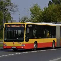 Żółto-czerwony autobus przegubowy linii 135 z napisem "PL.HALLERA" na wyświetlaczu.