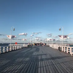 Spacer po molo w Sopocie, idealne miejsce na spacer po przyjeździe z Gdańska. Widać ludzi, ławki i latarnie.