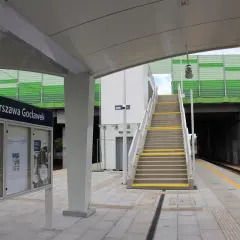 Nowoczesne przystanki autobusowe i kolejowe na stacji Warszawa Gocławek. Schody prowadzą na zieloną kładkę nad torami.