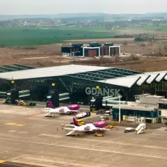Samoloty Wizz Air i Lufthansa na płycie lotniska Gdańsk. W tle nowoczesny terminal i krajobraz.