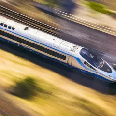 Pociąg PKP Intercity pędzi z ogromną prędkością, rozmazując krajobraz.