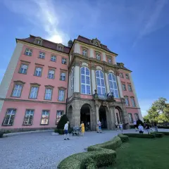 Zamek Książ, łatwy dojazd PKP, zachwyca różową fasadą i barokową architekturą. Turyści spacerują po brukowanym dziedzińcu.