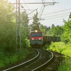 Pociąg towarowy mknie po torach wśród zieleni. Marzysz, jak zostać maszynistą? To podróż pełna odpowiedzialności i pięknych widoków.