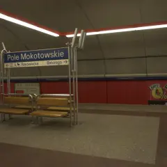 Na stacji metra Pole Mokotowskie stoi mężczyzna obok ławki. W tle niebieska tablica z nazwami ulic i czerwone panele.