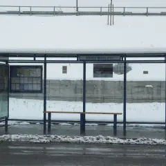 Przystanek Rondo Mogilskie zasypany śniegiem. Wiaty, ławka i kosz na śmieci pokryte białym puchem.