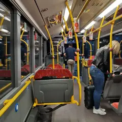 Wnętrze autobusu, żółte poręcze, siedzenia, pasażerowie z bagażem. Zadar komunikacja miejska.