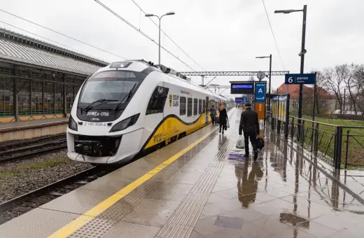 Pasażerowie wsiadają do pociągu, a obok stoi hulajnoga elektryczna.