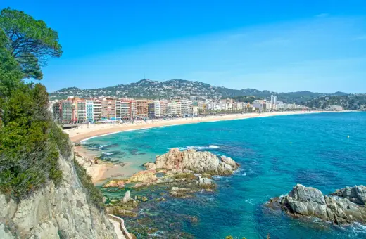 Widok na plażę w Lloret de Mar z klifów. W oddali widać zabudowania i wzgórza. Idealne miejsce na wakacje, niedaleko od lotniska.