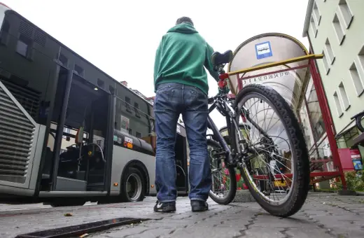 Mężczyzna z rowerem czeka na autobus.