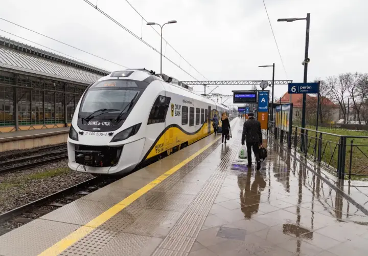Pasażerowie wsiadają do pociągu, a obok stoi hulajnoga elektryczna.