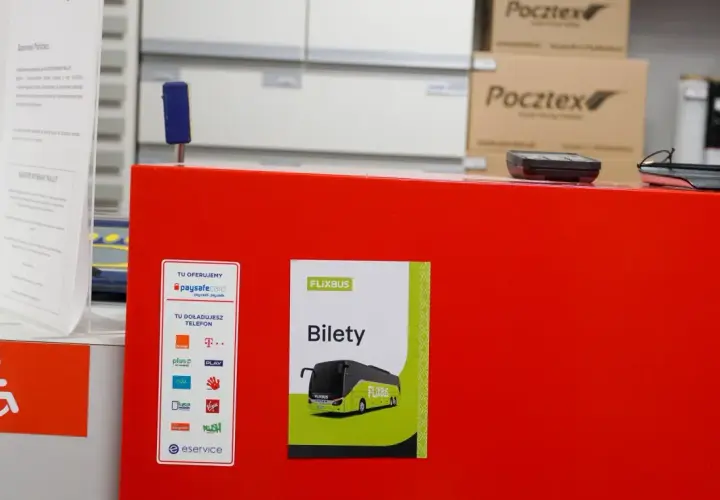 Na czerwonym blacie znajduje się plakat z napisem "FLIXBUS Bilety". To miejsce, gdzie kupisz bilet na Flixbus.