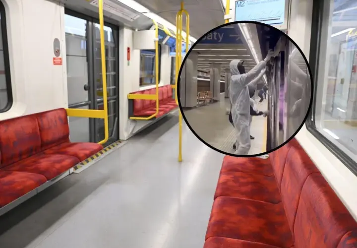 Wnętrze pustego wagonu metra M2, gdzie pracownicy w kombinezonach dezynfekują drzwi.