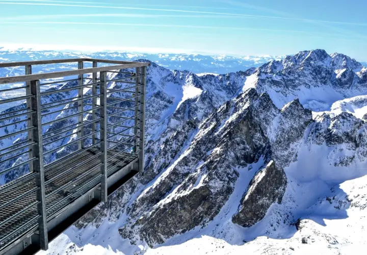 Metalowa kładka widokowa z widokiem na ośnieżone szczyty Tatr Wysokich. Niesamowita panorama Tatrzańskiej Łomnicy.