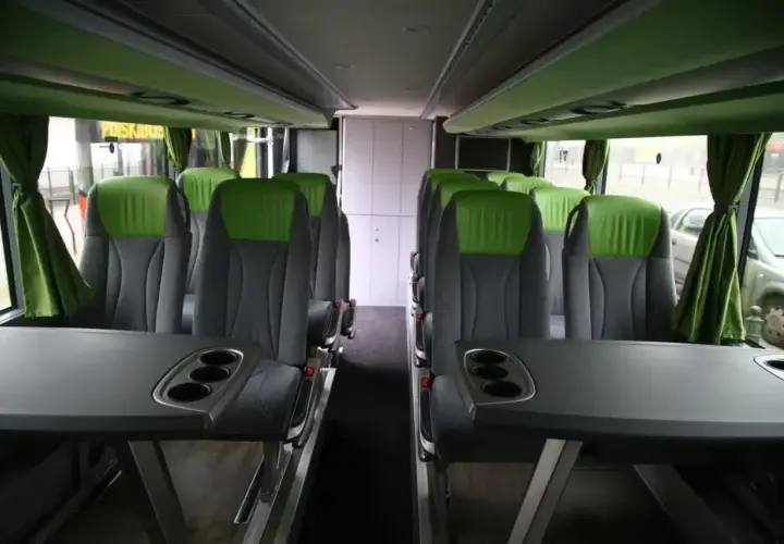 Wygodne, zielono-szare fotele w autobusie FlixBus, z rozkładanymi stolikami i uchwytami na kubki.