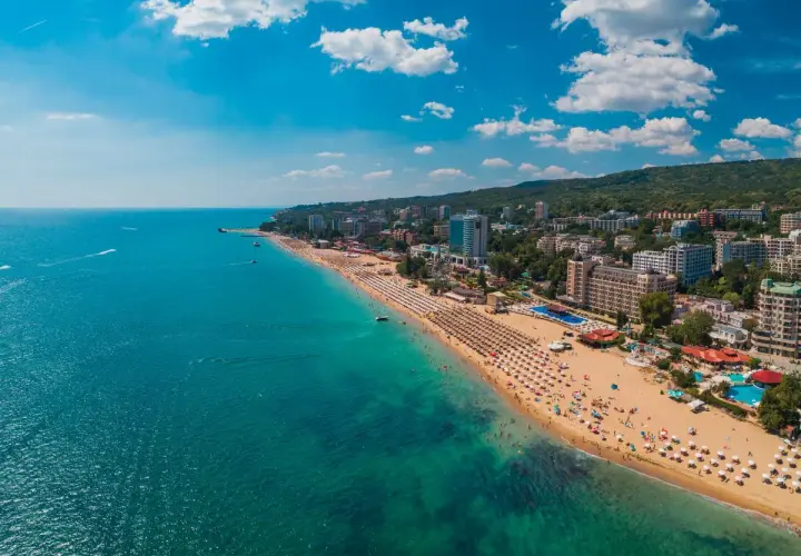 Słoneczna plaża w Złote Piaski, z turkusowym morzem i hotelami w tle. Idealne miejsce na wakacje, niedaleko lotniska.