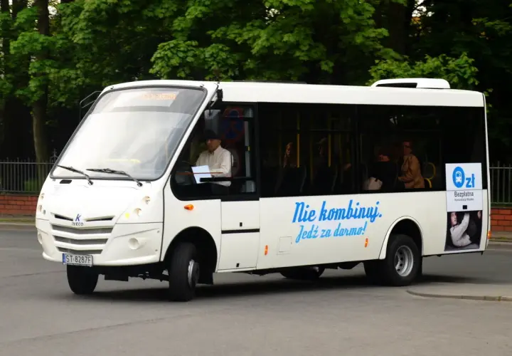 Białe autobusy w Żorach oferują bezpłatną komunikację miejską. Kierowca i pasażerowie w środku.