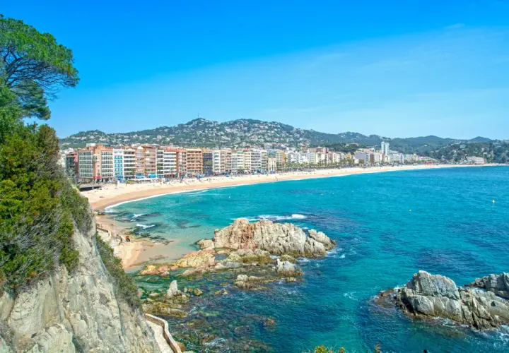 Widok na plażę w Lloret de Mar z klifów. W oddali widać zabudowania i wzgórza. Idealne miejsce na wakacje, niedaleko od lotniska.