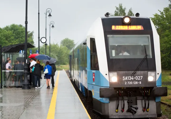 Szynobus Lublin - Zamość trasa. Pasażerowie z parasolami czekają na deszczowy dzień na peronie.
