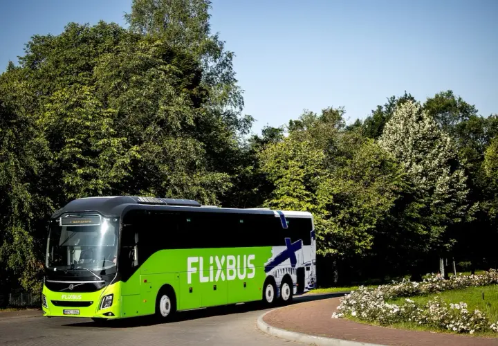 Zielony Flixbus na tle zieleni i błękitnego nieba. Piękne miejsce na podróż.