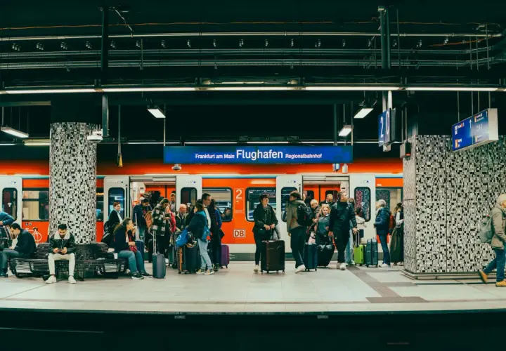 Ludzie z bagażami czekają na pociąg na stacji Regionalbahnhof na lotnisku we Frankfurcie.