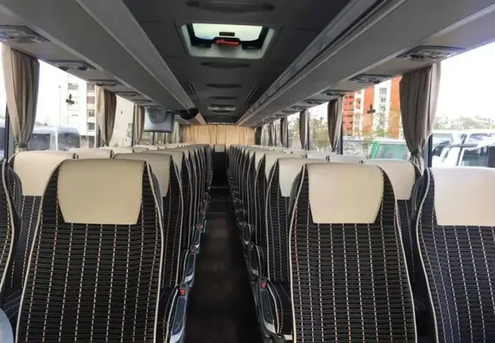 Wnętrze autobusu ze Słowenii, rzędy wygodnych siedzeń z czarno-białą tapicerką i jasnymi zagłówkami.