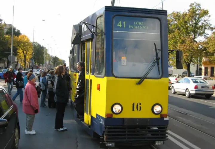 Żółto-niebieski tramwaj linii 41 Łódź Pabianice stoi na przystanku, czekając na pasażerów.
