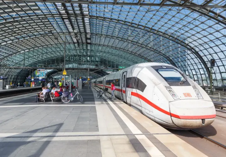 Biały pociąg ICE na peronie pod szklanym dachem. Berlin Dworzec Główny, ludzie czekają na pociąg z rowerami.