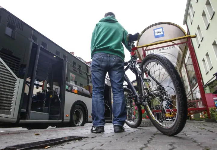 Mężczyzna z rowerem czeka na autobus.